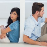 Sitting couple are separated by wall with woman looking at camer